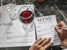 Čaša crvenog vina i bilješke koje su sastavni dio team building program za pripremu vinskog blenda